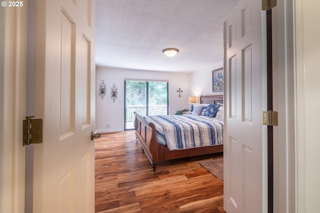 5 Woodthrush Ln, Gleneden Beach, OR 97388 - bedroom with light wood-style flooring, access to outside, a textured ceiling, and baseboards