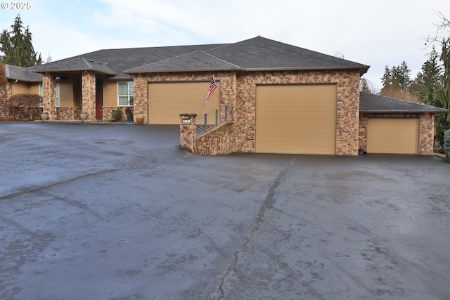 prairie-style home featuring a garage, roof with shingles, and driveway