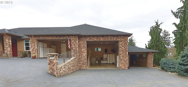 view of front facade featuring driveway, an attached garage, and roof with shingles