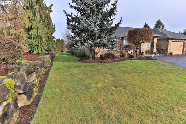 view of front of home with an attached garage, aphalt driveway, and a front lawn