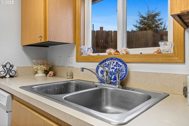 kitchen with light countertops, white dishwasher, and a sink