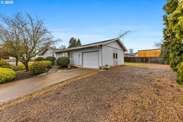 view of front of house with a garage, concrete driveway, and fence