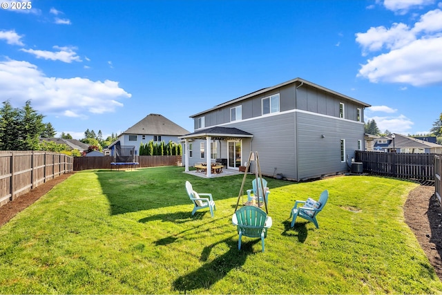 2625 NE 8th Ave, Battle Ground, WA 98604 - back of property featuring a trampoline, an outdoor fire pit, a patio, central air condition unit, and board and batten siding