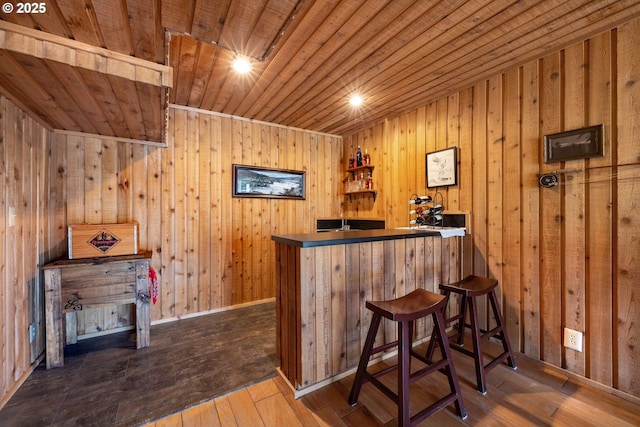 bar featuring hardwood / wood-style flooring, wood walls, wood ceiling, and bar