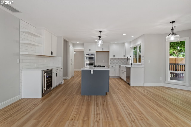 kitchen featuring pendant lighting, stainless steel appliances, wine cooler, white cabinets, and a kitchen island