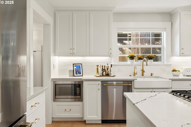 364 Northshore Rd, Lake Oswego, OR 97034 - kitchen featuring appliances with stainless steel finishes, decorative backsplash, white cabinets, and light stone counters