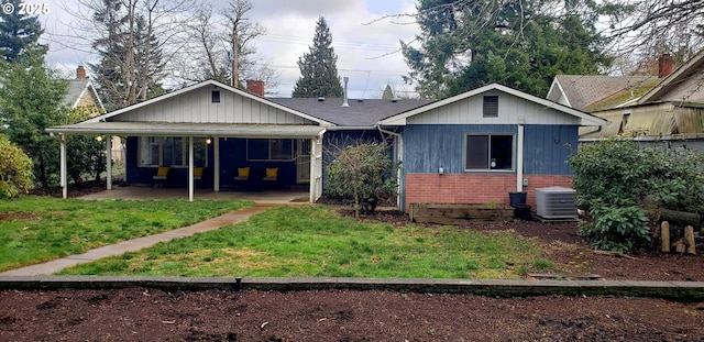 back of property with central AC, a carport, and a lawn