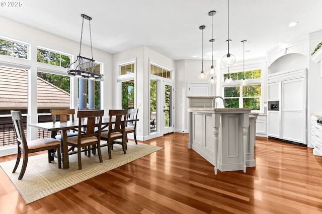 kitchen with paneled built in fridge, dark wood finished floors, a chandelier, a kitchen island with sink, and recessed lighting