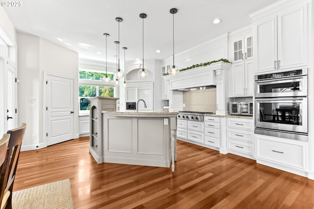 kitchen with stainless steel appliances, wood finished floors, white cabinets, backsplash, and recessed lighting