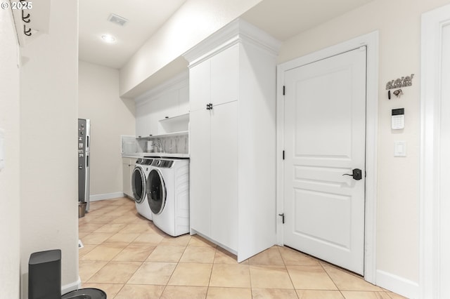 washroom with washer and clothes dryer, light tile patterned floors, cabinet space, and baseboards
