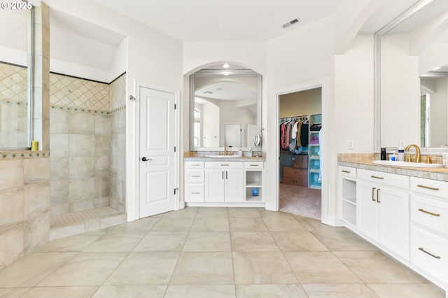 full bathroom featuring walk in shower, tile patterned flooring, two vanities, a walk in closet, and plenty of natural light