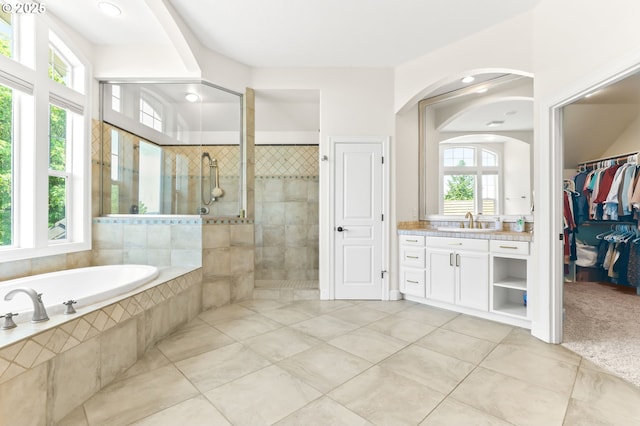 full bath featuring tile patterned floors, a tile shower, a garden tub, vanity, and a walk in closet
