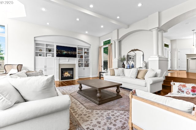 living room featuring decorative columns, wood finished floors, recessed lighting, arched walkways, and a glass covered fireplace