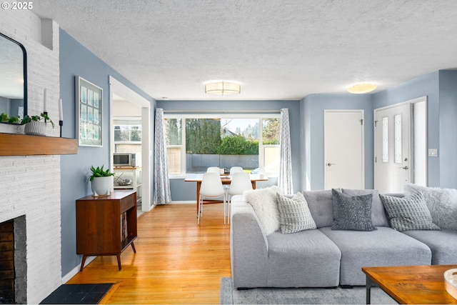 living room with cooling unit, a fireplace, light hardwood / wood-style floors, and a textured ceiling