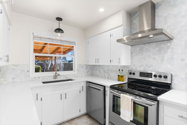 kitchen with sink, hanging light fixtures, appliances with stainless steel finishes, wall chimney range hood, and white cabinets