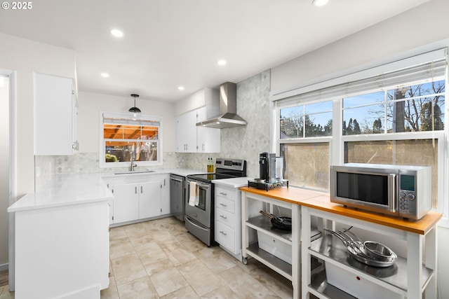 kitchen featuring appliances with stainless steel finishes, white cabinetry, sink, decorative backsplash, and wall chimney exhaust hood