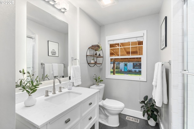 bathroom featuring vanity, a shower with door, and toilet