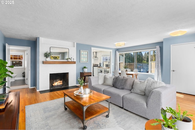 living room featuring a fireplace, light hardwood / wood-style floors, and a textured ceiling