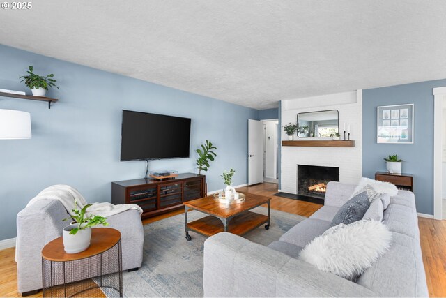 living room with a textured ceiling, a fireplace, and light hardwood / wood-style flooring