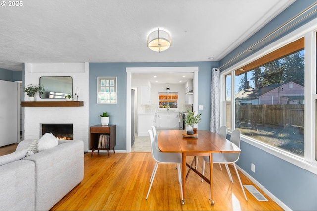 dining room with a fireplace and light hardwood / wood-style flooring