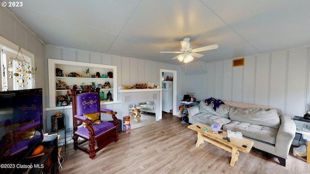 living room featuring ceiling fan, built in features, and light wood-type flooring