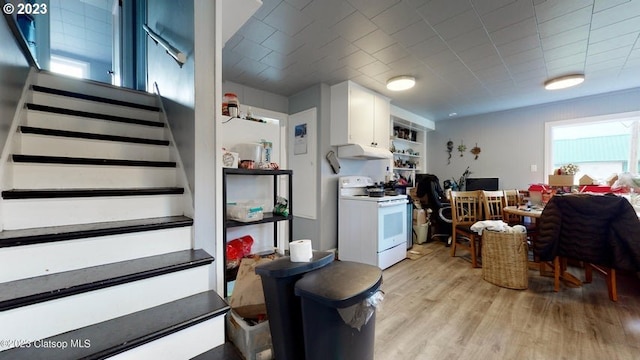 kitchen with white cabinets, white range with electric stovetop, light wood-type flooring, and extractor fan