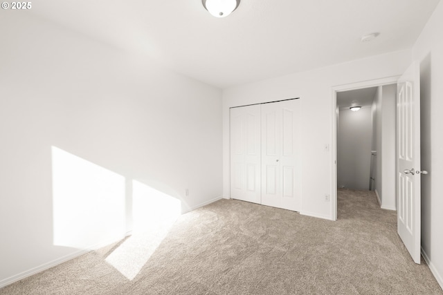 unfurnished bedroom featuring light carpet and a closet