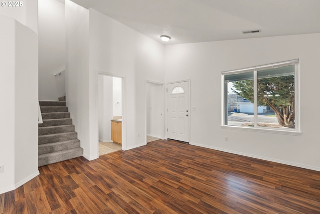 foyer entrance featuring dark wood-type flooring and high vaulted ceiling