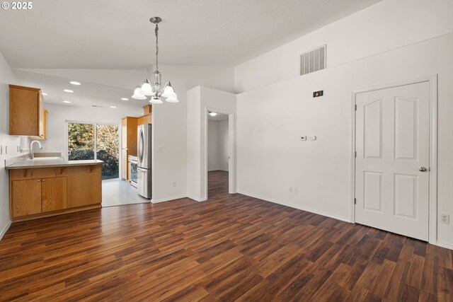 kitchen featuring dark hardwood / wood-style flooring, lofted ceiling, stainless steel refrigerator, and kitchen peninsula