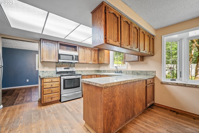 5807 NE 152nd Ave, Vancouver, WA 98682 - kitchen featuring stainless steel appliances, a peninsula, light wood-style flooring, light countertops, and a textured ceiling