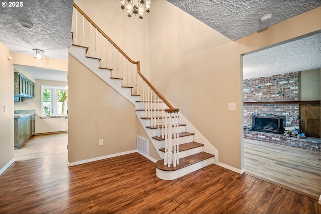 5807 NE 152nd Ave, Vancouver, WA 98682 - stairway with wood finished floors, a textured ceiling, a brick fireplace, and a chandelier