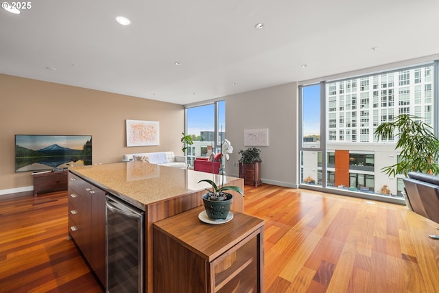 841 S Gaines St Unit 714, Portland, OR 97239 - kitchen featuring beverage cooler, open floor plan, a kitchen island, a wall of windows, and recessed lighting