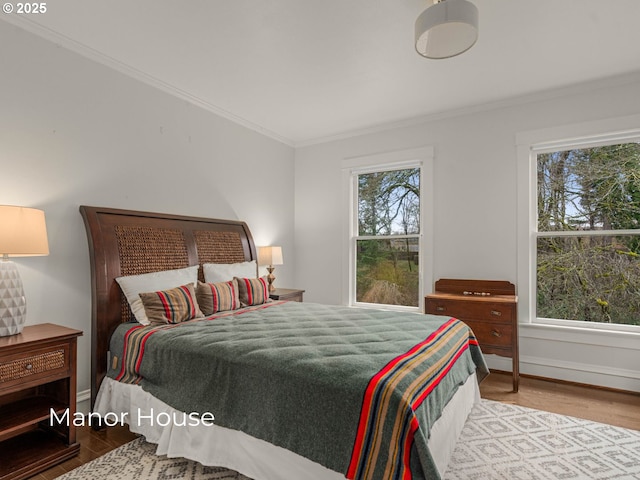 bedroom featuring wood finished floors, baseboards, and ornamental molding