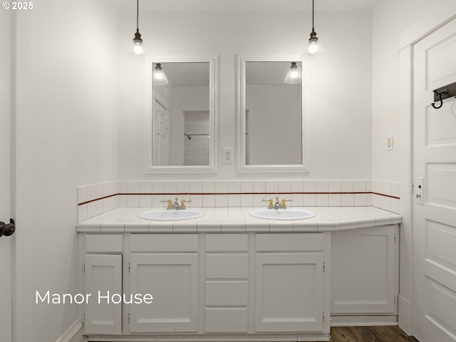 bathroom with double vanity, wood finished floors, and a sink