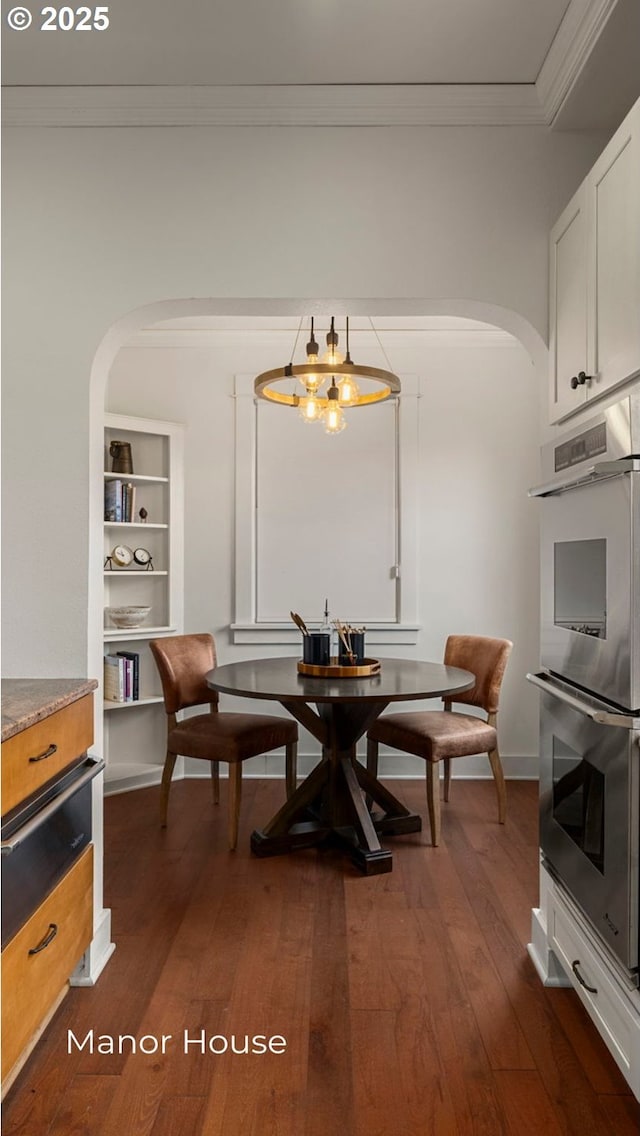 dining room featuring crown molding, arched walkways, and dark wood-style flooring