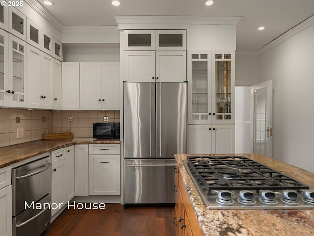 kitchen with dark wood-style floors, white cabinetry, appliances with stainless steel finishes, crown molding, and decorative backsplash