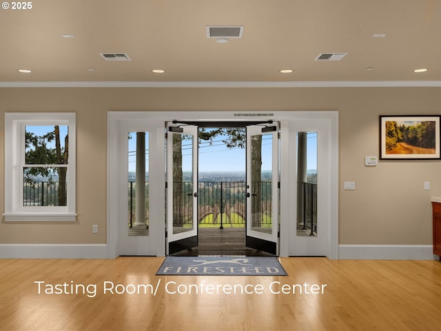 foyer entrance with wood finished floors, visible vents, and ornamental molding