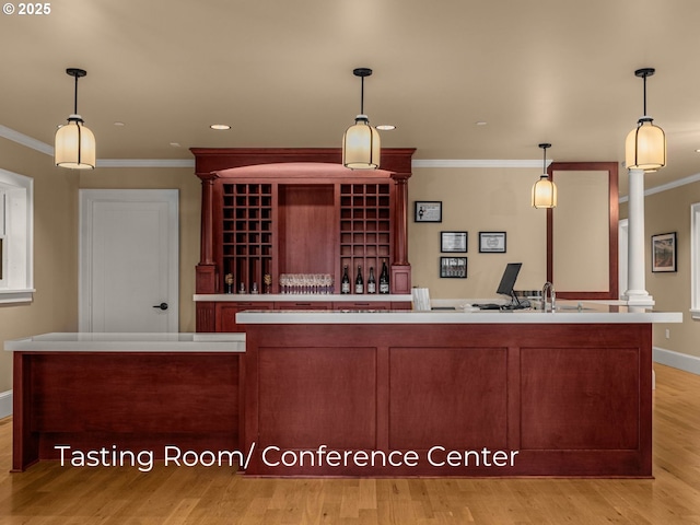 kitchen featuring hanging light fixtures, light wood-type flooring, crown molding, and ornate columns