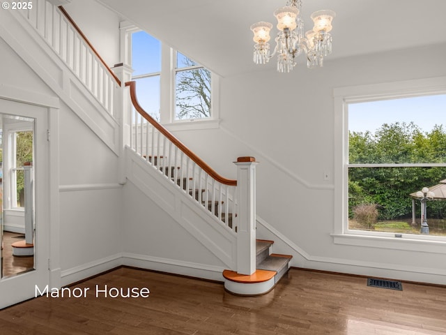 stairway featuring visible vents, baseboards, an inviting chandelier, and wood finished floors