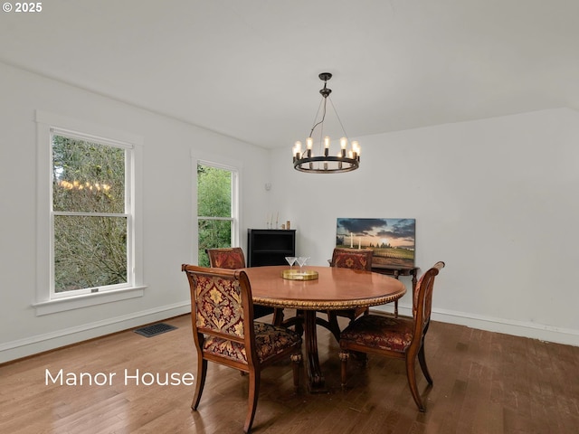 dining area featuring visible vents, baseboards, a notable chandelier, and wood finished floors