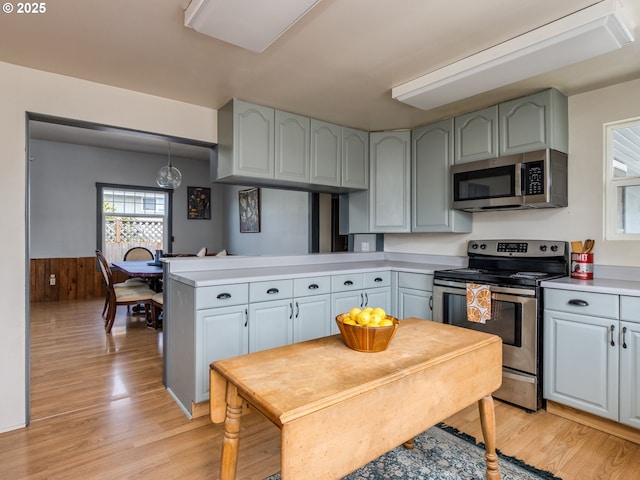 486 S Knott St, Canby, OR 97013 - kitchen with stainless steel appliances, a peninsula, light wood-type flooring, wainscoting, and light countertops