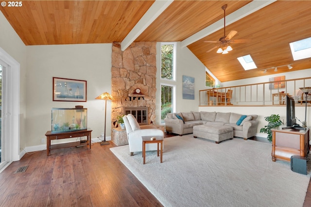 living room with a skylight, a fireplace, wood finished floors, wooden ceiling, and beamed ceiling