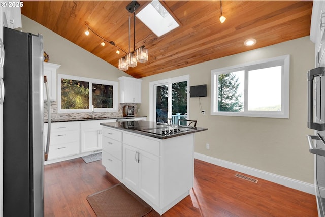 kitchen with wood ceiling, dark countertops, backsplash, and freestanding refrigerator