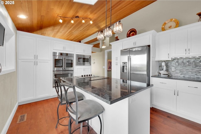 kitchen with visible vents, wood ceiling, wood finished floors, stainless steel appliances, and backsplash