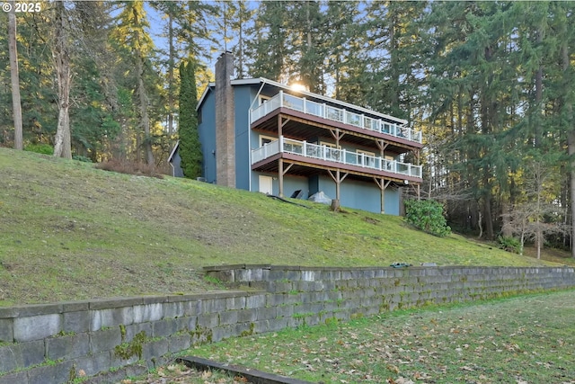 back of property with a deck, a yard, and a chimney