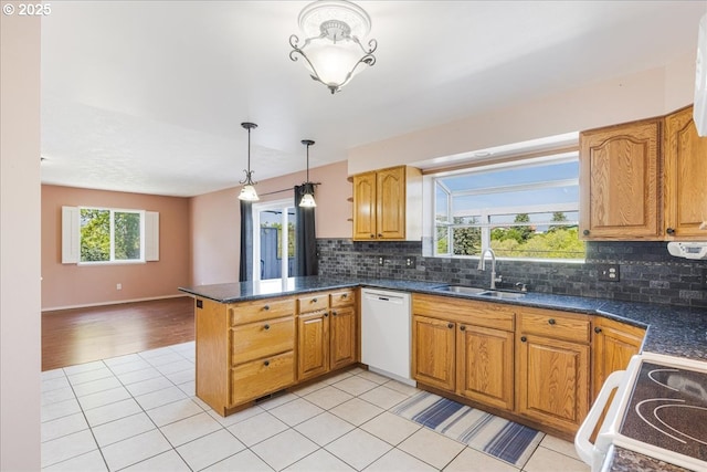 1825 Minnesota St, The Dalles, OR 97058 - kitchen with decorative backsplash, a peninsula, dark countertops, white appliances, and a sink