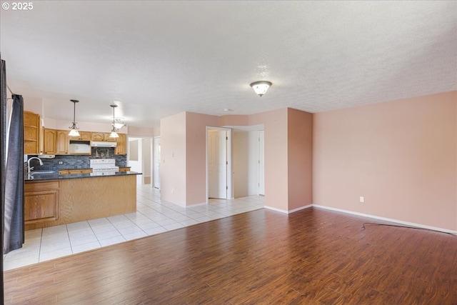 1825 Minnesota St, The Dalles, OR 97058 - interior space featuring decorative backsplash, dark countertops, stove, open floor plan, and under cabinet range hood