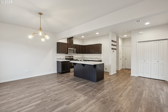 kitchen featuring a chandelier, appliances with stainless steel finishes, hardwood / wood-style flooring, dark brown cabinets, and decorative light fixtures