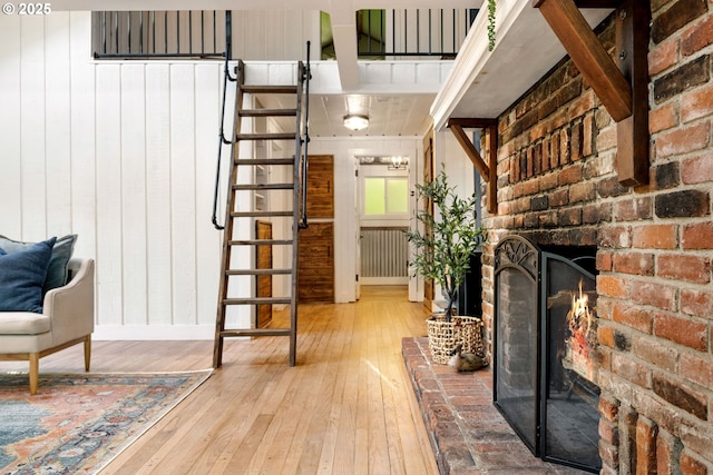 988 Savage Creek Rd, Grants Pass, OR 97527 - unfurnished living room featuring wood-type flooring, a brick fireplace, wooden walls, and stairs