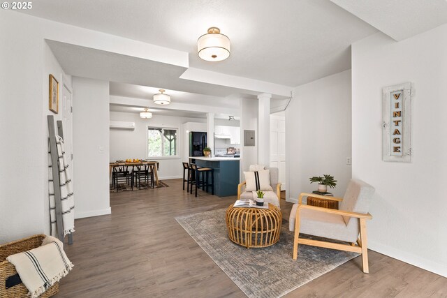 988 Savage Creek Rd, Grants Pass, OR 97527 - sitting room featuring wood finished floors, baseboards, decorative columns, and a wall mounted AC